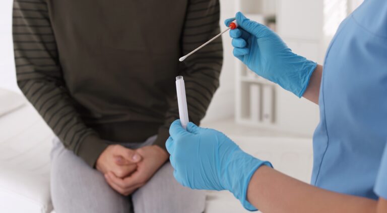 Doctor taking sample for STD testing from man in clinic, closeup