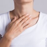 Closeup Of Young Woman with her Hand Touching Her Neck at her throat.