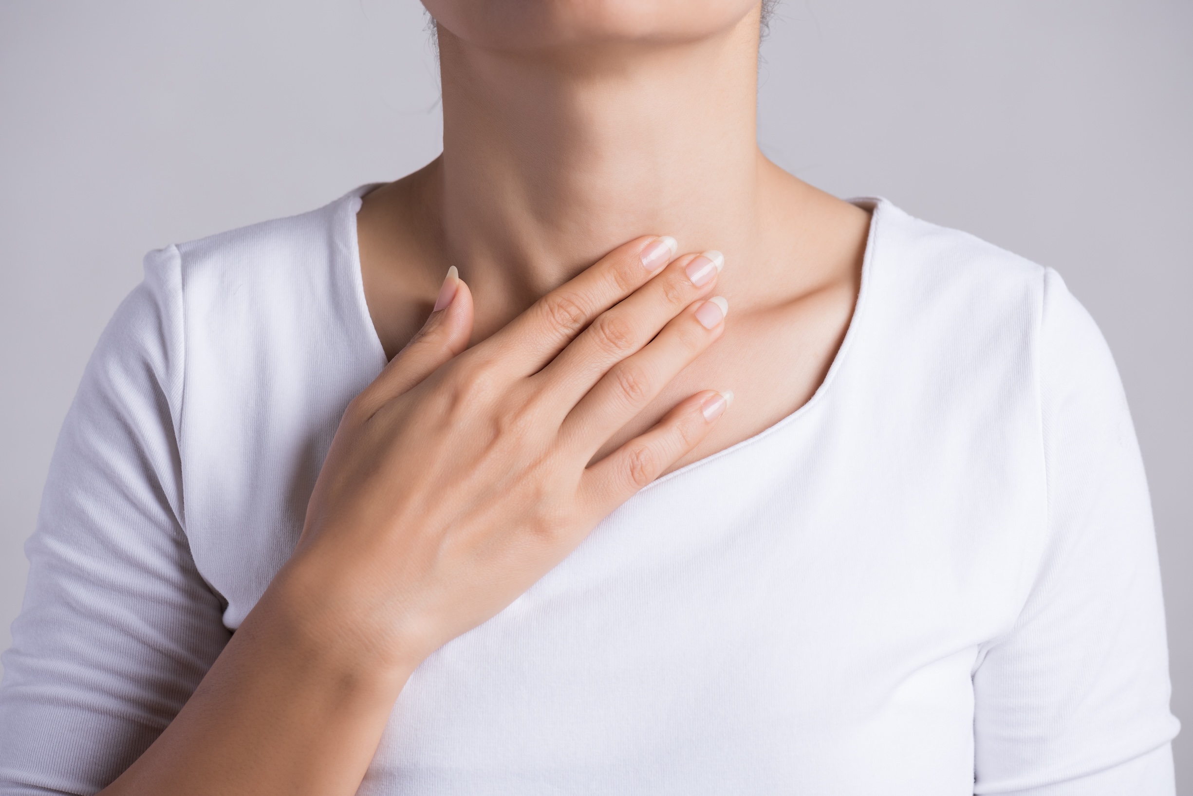 Closeup Of Young Woman with her Hand Touching Her Neck at her throat.