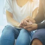 A closeup of couple holding hands, comforting one another during the difficult conversation of an STD diagnosis.