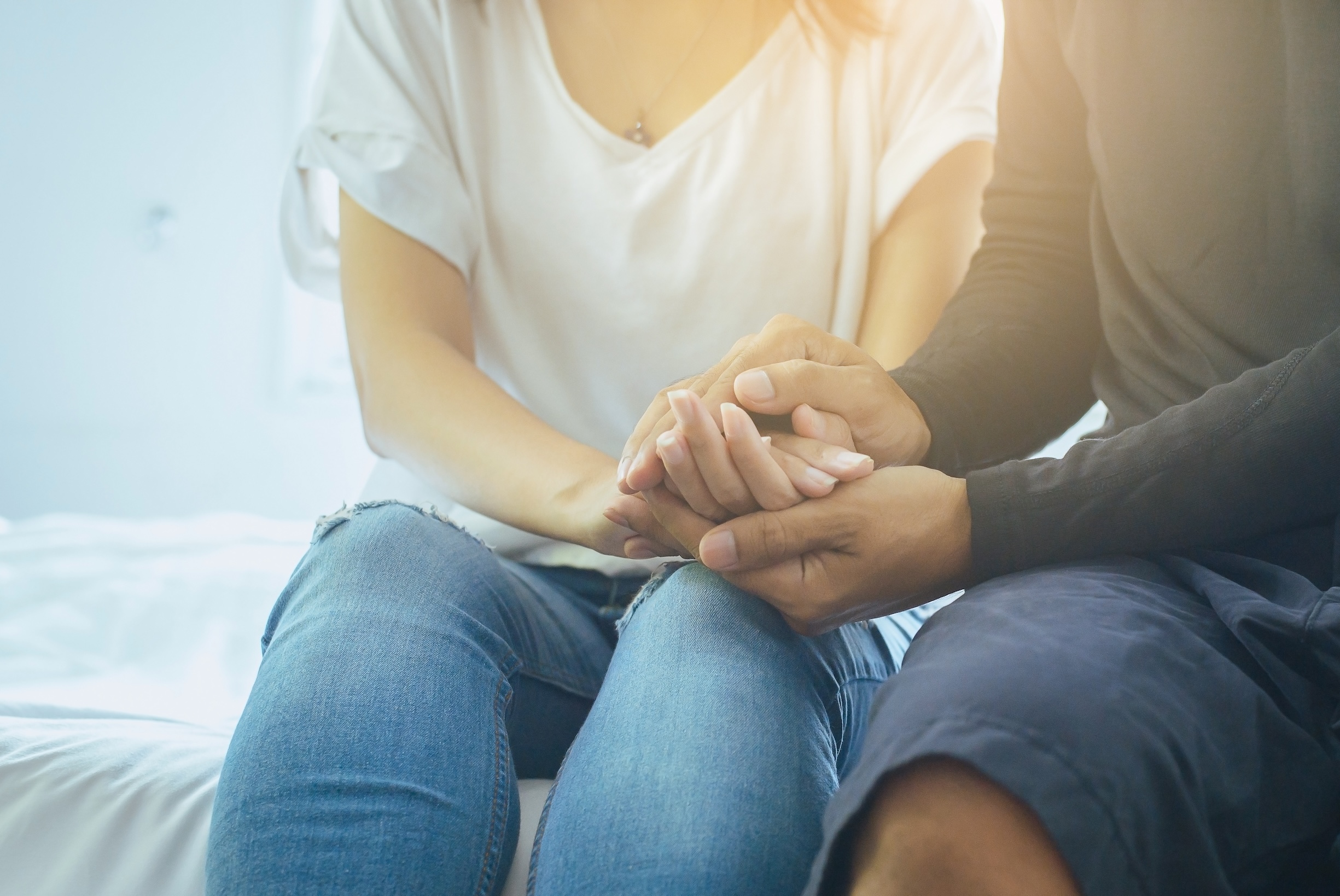 A closeup of couple holding hands, comforting one another during the difficult conversation of an STD diagnosis.