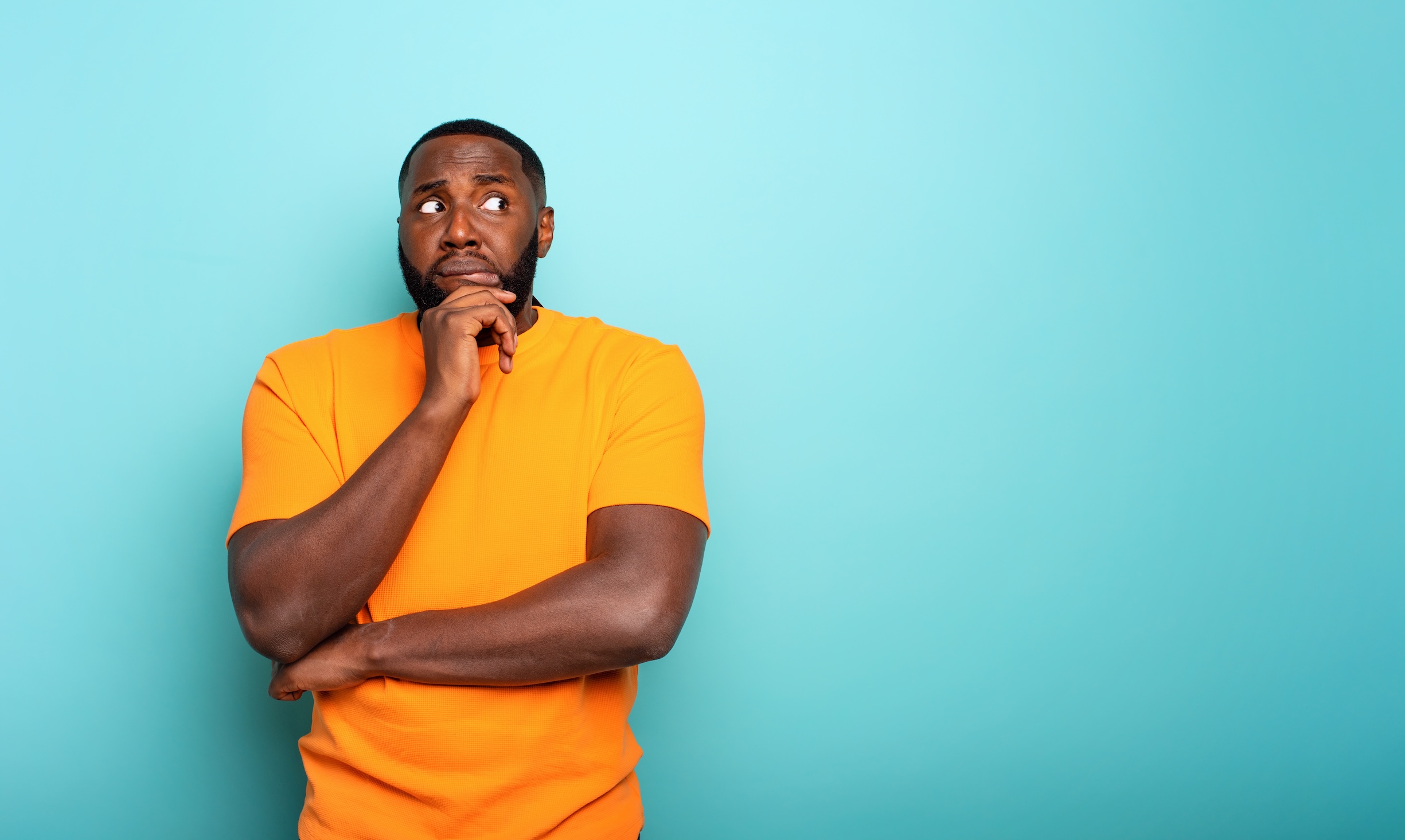 A confused and somewhat concerned black man wearing a yellow shirt, questioning whether an STD can be contracted without sex.